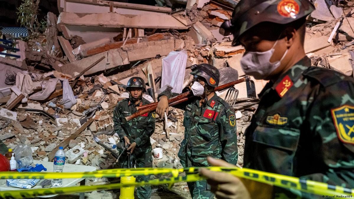 Vietnamese rescuers standing next to rubble