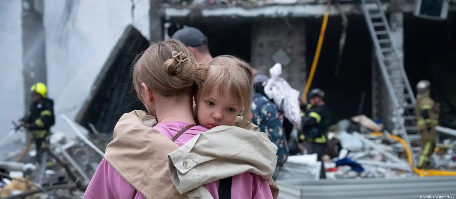 En la imagen aparece una madre con su hija en brazos en medio de la destrucción de edificios tras los ataques rusos en Kiev.