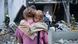 En la imagen aparece una madre con su hija en brazos en medio de la destrucción de edificios tras los ataques rusos en Kiev. En la imagen aparece una madre con su hija en brazos en medio de la destrucción de edificios tras los ataques rusos en Kiev.