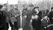 A family smiles among men in Nazi uniforms. 
