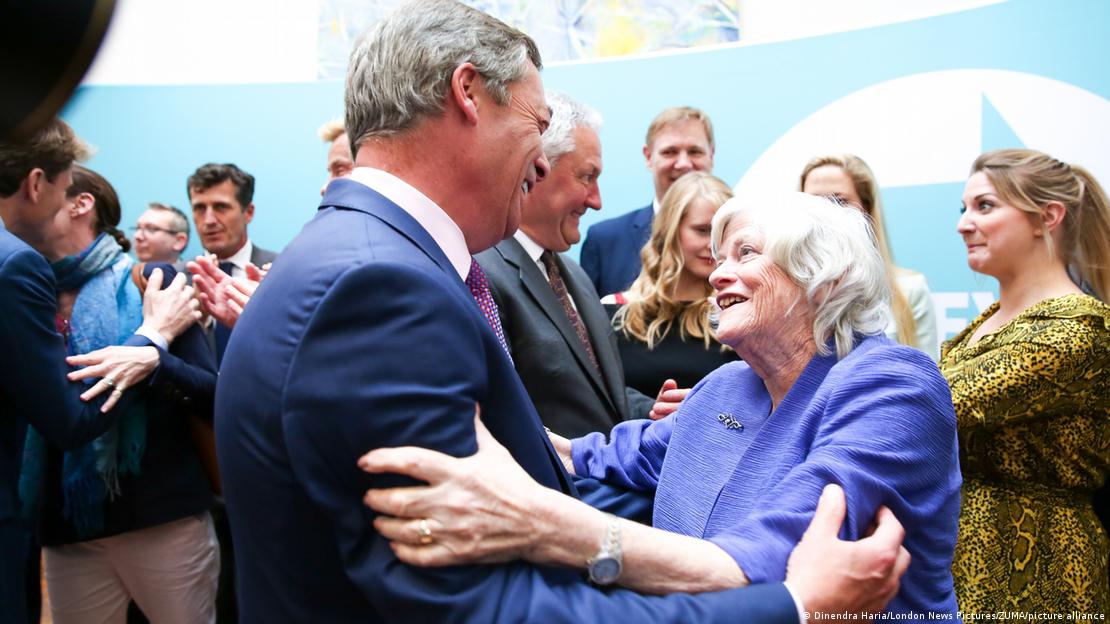 Nigel Farage e Ann Widdecombe se comprimentam em um evento em 2029