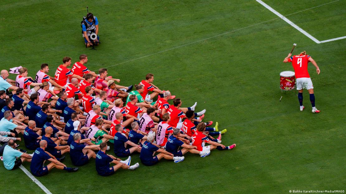 Haaland golpeando el tambor para hacer el remo vikingo junto a sus compañeros de equipo y la afición noruega.