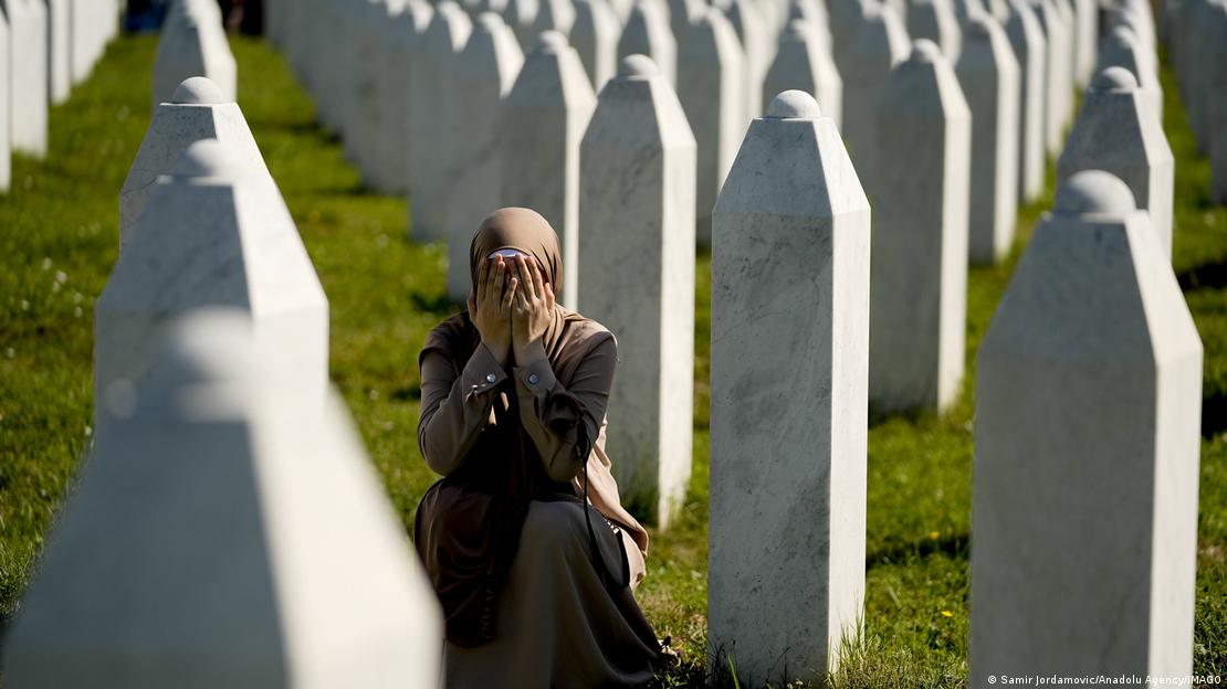 Potocari'deki Srebrenitsa Anıt Mezarlığı'nda bir kadın mezar taşlarının arasında oturmuş y&uuml;z&uuml;n&uuml; elleriyle kapatıyor