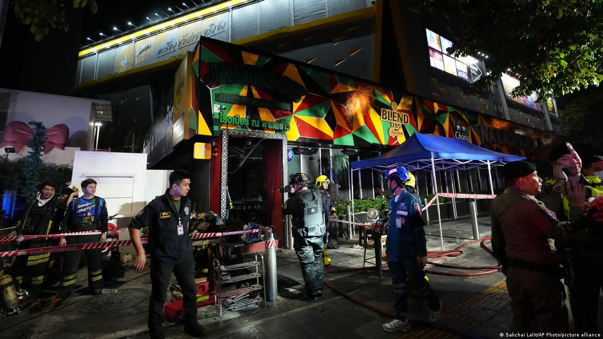 Rescuers stand near the site of a fire in Bangkok, Thailand