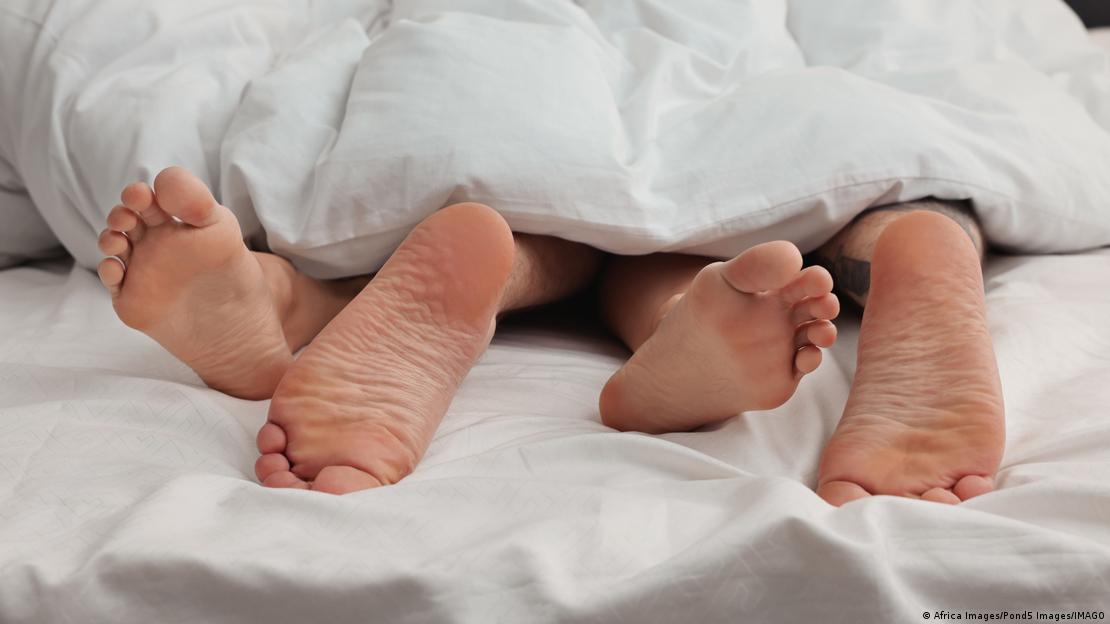 Pés de um casal sob uma manta sugerem um ato sexual