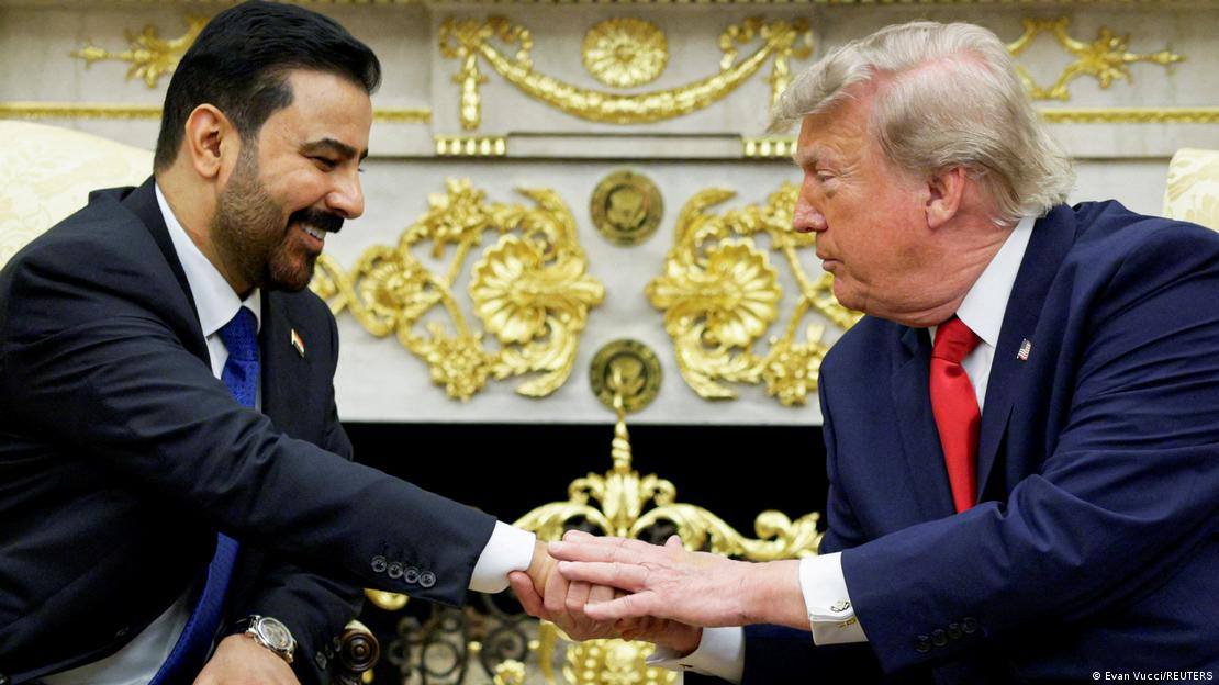 Irak Başbakanı Ali el-Zeydi ile ABD Başkanı Donald Trump, oturdukları koltuklardan birbirlerine uzanarak tokalaşıyor