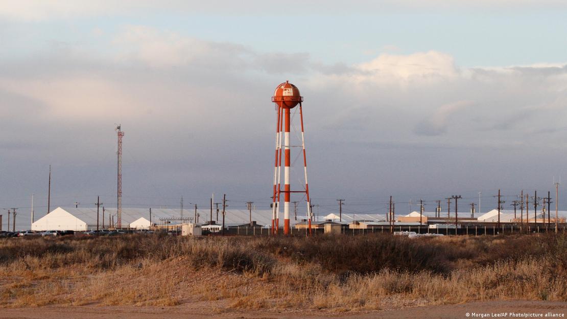 Un tanque rojo y blanco elevado en medio de una serie de tiendas de campaña reforzadas en el centro de detención de inmigrantes Camp East Montana se alza imponente en el desierto, dentro de una base del Ejército de EE. UU. a las afueras de El Paso, Texas. Un tanque rojo y blanco elevado en medio de una serie de tiendas de campaña reforzadas en el centro de detención de inmigrantes Camp East Montana se alza imponente en el desierto, dentro de una base del Ejército de EE. UU. a las afueras de El Paso, Texas.