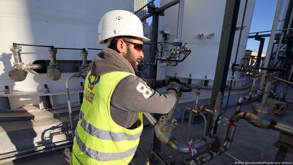 Ein Arbeiter in Schutzkleidung dreht am Ventil einer Rohranlage. Ein Arbeiter in Schutzkleidung dreht am Ventil einer Rohranlage.
