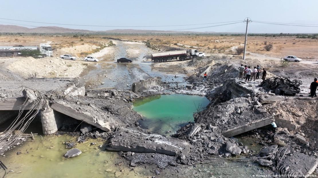 An aerial view shows men standing near burned vehicles on a destroyed bridge as traffic uses a dirt bypass near Bandar Abbas, Iran, on July 17, 2026 An aerial view shows men standing near burned vehicles on a destroyed bridge as traffic uses a dirt bypass near Bandar Abbas, Iran, on July 17, 2026