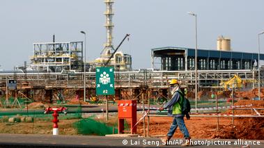 Image 3: A masked man wearing a construction helmet walks past a rare earths refinery construction site in Gebeng, Malaysia (April 19, 2012)