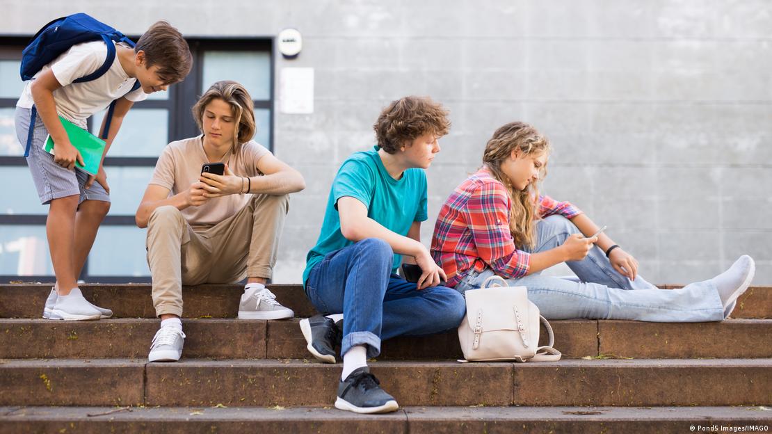 Varios chicos y chicas, acomodados en una escalera junto a un centro educativo, observan sus teléfonos celulares. Varios chicos y chicas, acomodados en una escalera junto a un centro educativo, observan sus teléfonos celulares.