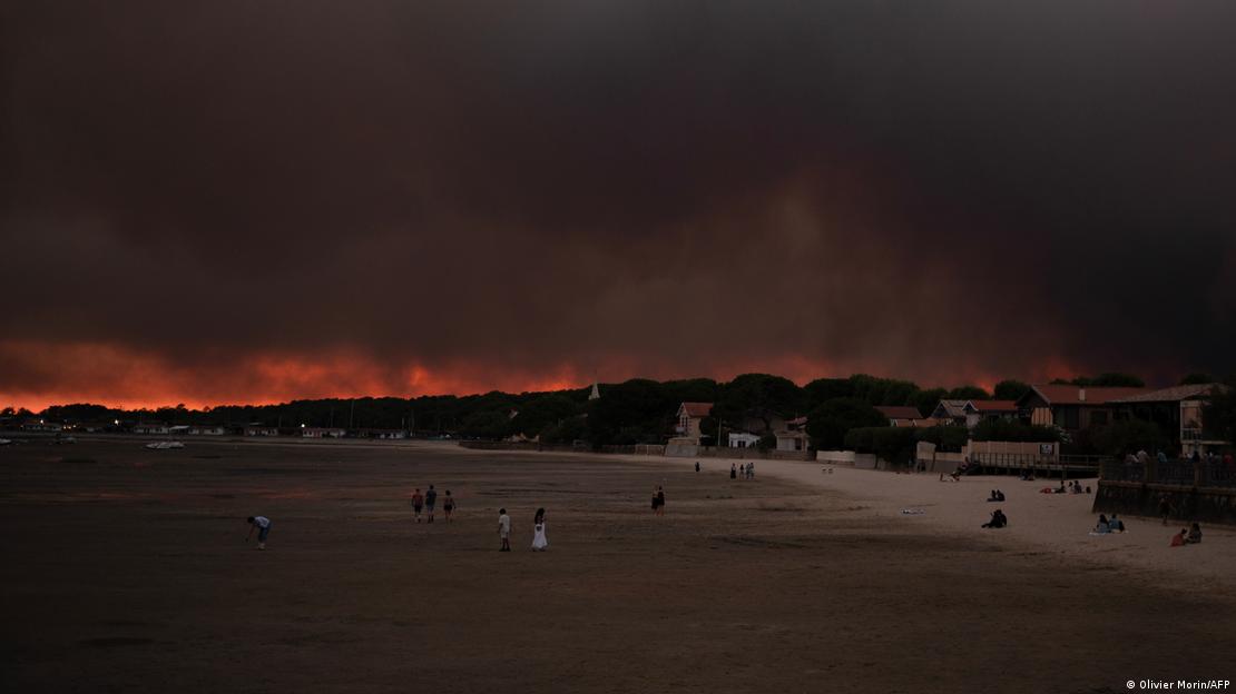 Uma praia está completamente às escuras devido à fumaça dos incêndios em suas proximidades.