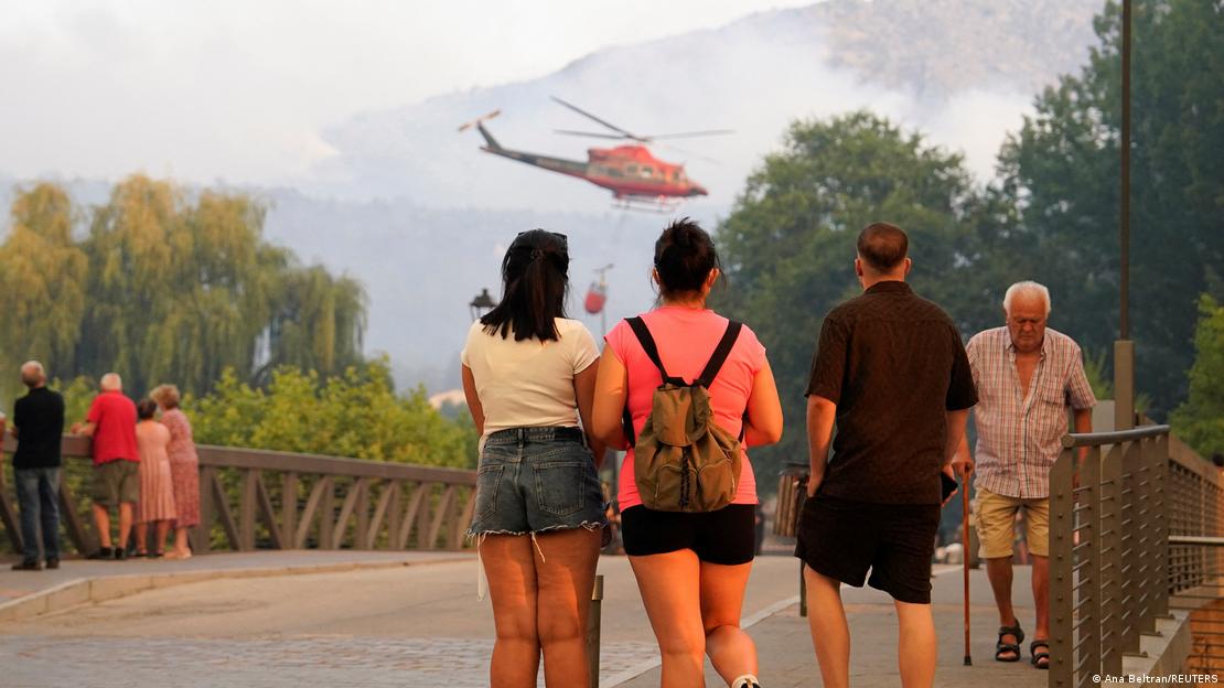 Navaluenga, Avila: varias personas observan un incendio forestal en Ávila, y un helicóptero sobrevuela el lugar. Navaluenga, Avila: varias personas observan un incendio forestal en Ávila, y un helicóptero sobrevuela el lugar.
