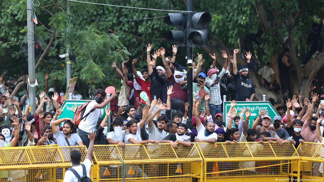 Un grupo de jóvenes levantan las manos subidos a vallas y en la capital de la India. Un grupo de jóvenes levantan las manos subidos a vallas y en la capital de la India.