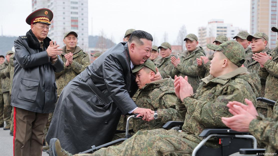 Kim Jong-un abraça um soldado que está sentado em uma cadeira de rodas
