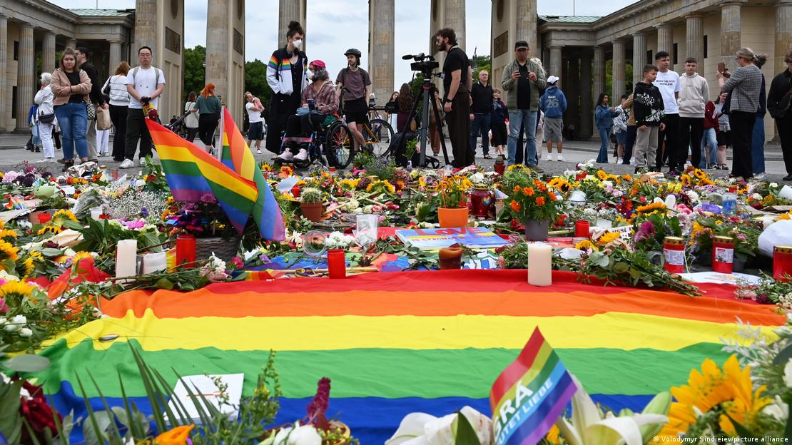 Menschen stehen vor Blumen und Kerzen, die an einem provisorischen Gedenkort für die Opfer des Anschlags während des Christopher Street Day (CSD) niedergelegt wurden, am Brandenburger Tor in Berlin Menschen stehen vor Blumen und Kerzen, die an einem provisorischen Gedenkort für die Opfer des Anschlags während des Christopher Street Day (CSD) niedergelegt wurden, am Brandenburger Tor in Berlin