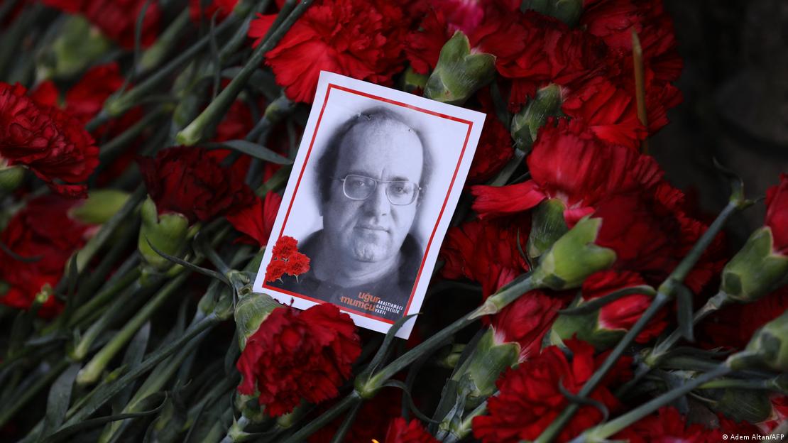 Uğur Mumcu'nun bir fotoğrafı kırmızı karanfiller üzerinde görülüyor Uğur Mumcu'nun bir fotoğrafı kırmızı karanfiller üzerinde görülüyor