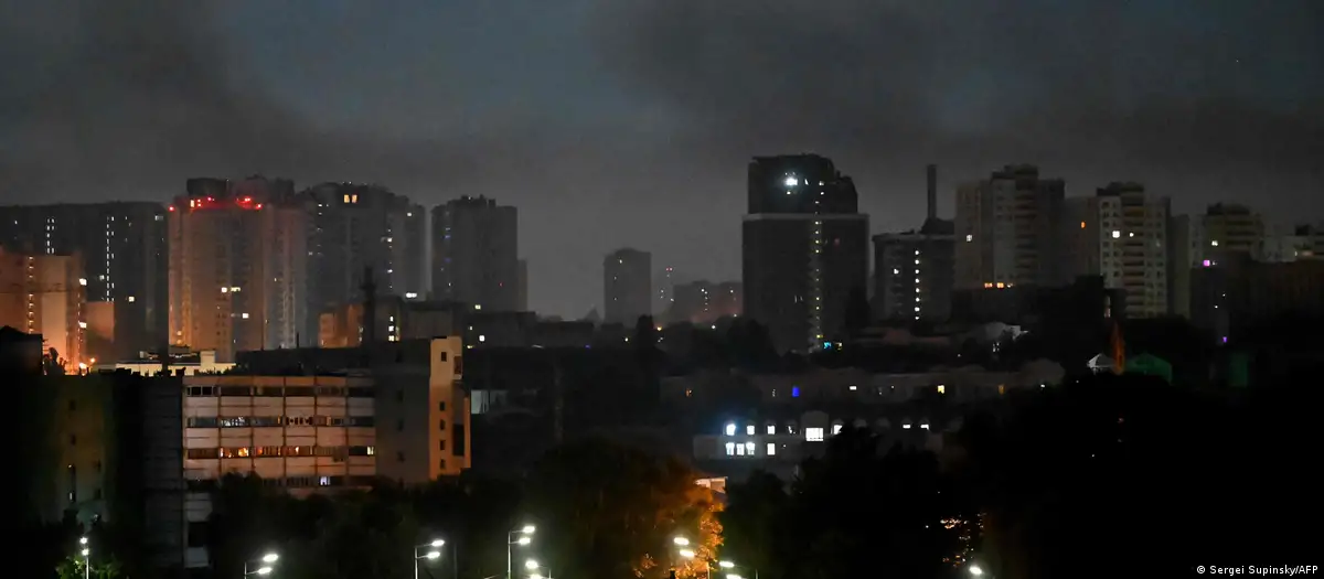 Vista nocturna de edificios urbanos iluminados bajo un cielo oscuro y brumoso