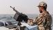 A sailor stands behinf a machine-gun aboard a vessel patrolling a shipping lane off Hanish Island in the Red Sea