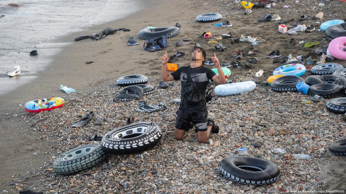 Jovem se ajoelha em praia em meio a boias