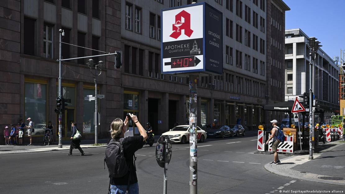 Un hombre toma foto a un indicador de temperatura den la calle. Un hombre toma foto a un indicador de temperatura den la calle.