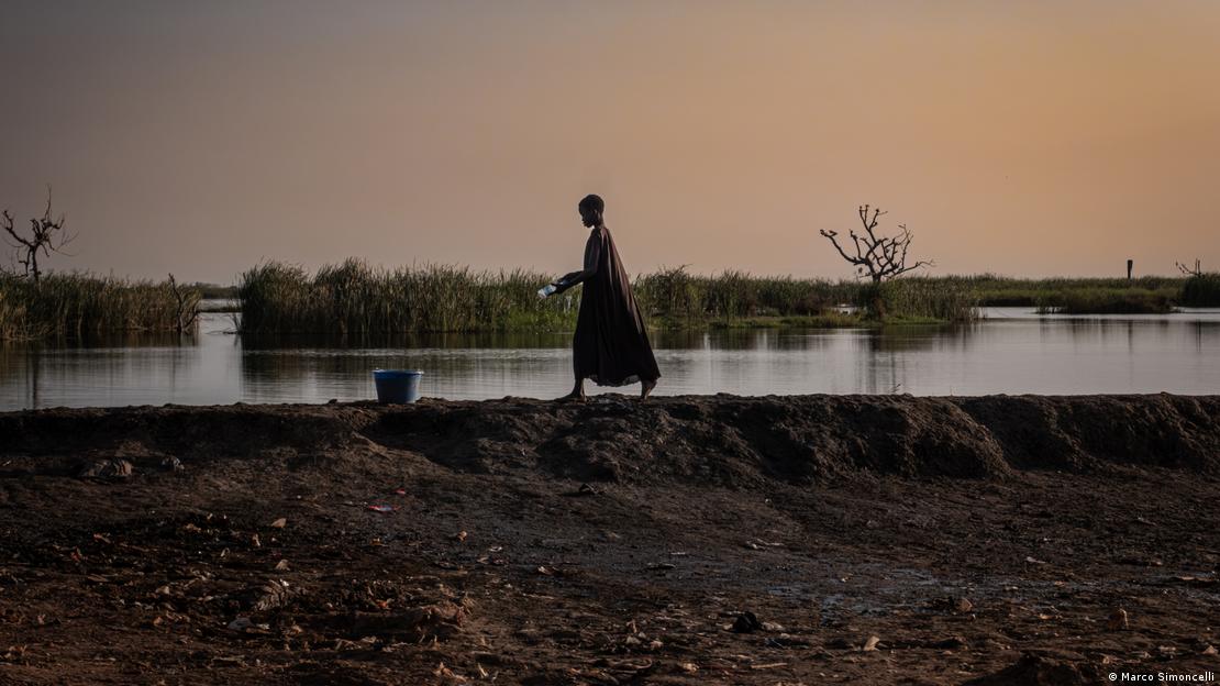 Jovem caminha ao longo de dique de terra em Bentiu