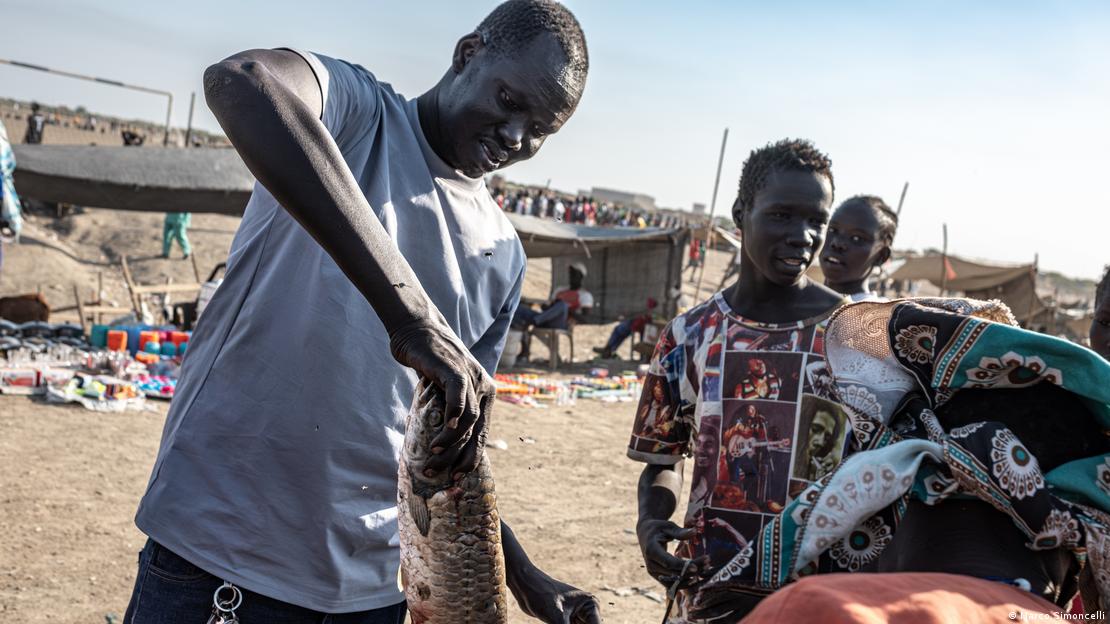 Pescador Simon Gatkuoth com peixe na mão Bentiu