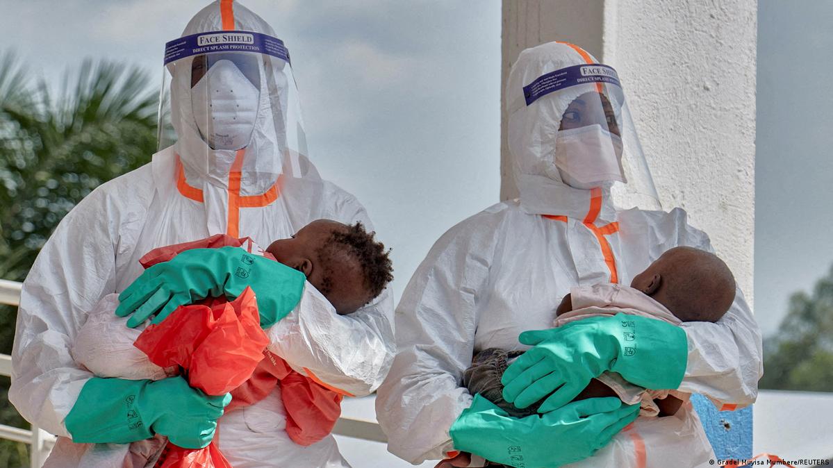 Congolese medical workers dressed in personal protective equipment (PPE) carry children tested and cleared off from Ebola from Saint Nicholas orphanage.