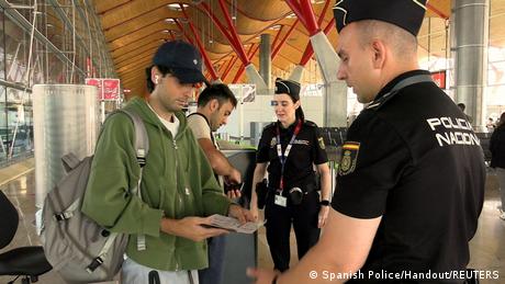 Ein Polizist kontrolliert am Flughafen Madrid die Papiere eines Einreisenden aus Italien (am Samstag)