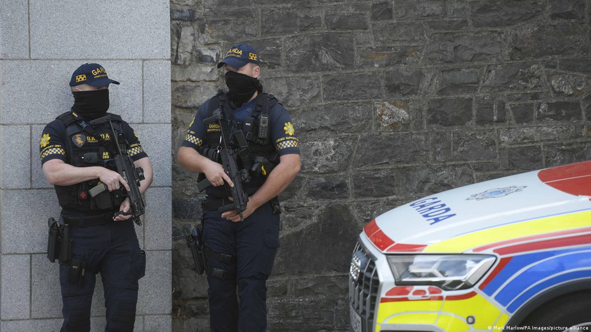 Two Irish Garda armed police officers with masks covering mouth and nose standing by police car