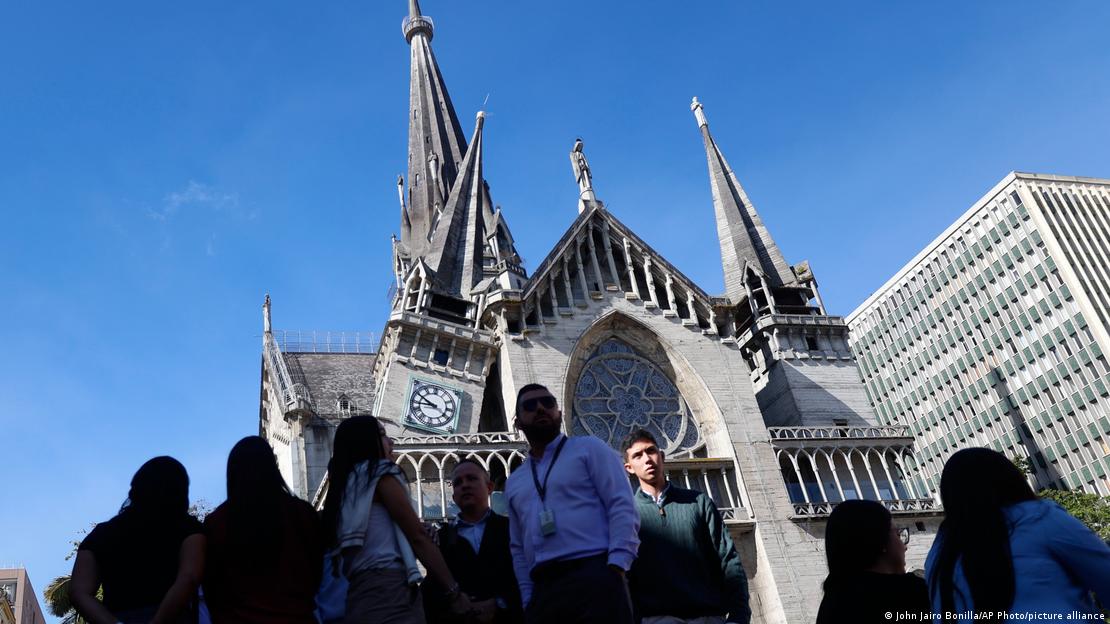 Manizales'teki neo-Gotik katedralin önünde toplanan insanlar, deprem sonrası hasarı incelerken görülüyor. Katedralin sol kulesi yan yatmış durumda.