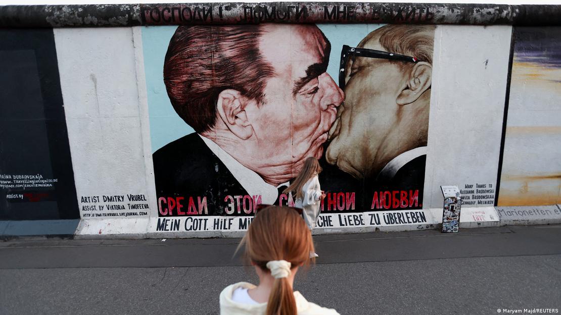 Un visitante observa un mural en una sección conservada del Memorial del Muro de Berlín, con una pintura creada en 1990 por el artista ruso Dmitri Vrúbel. Representa el histórico beso en la boca entre el líder soviético Leonid Brézhnev y el gobernante de Alemania Oriental Erich Honecker. Un visitante observa un mural en una sección conservada del Memorial del Muro de Berlín, con una pintura creada en 1990 por el artista ruso Dmitri Vrúbel. Representa el histórico beso en la boca entre el líder soviético Leonid Brézhnev y el gobernante de Alemania Oriental Erich Honecker.