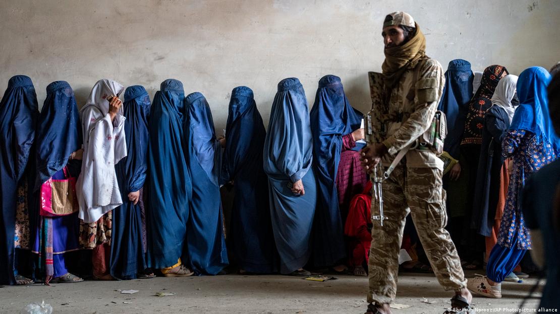 Mujeres afganas completamente cubiertas por burkas en una fila de distribución de alimentos en Kabul. Mujeres afganas completamente cubiertas por burkas en una fila de distribución de alimentos en Kabul.