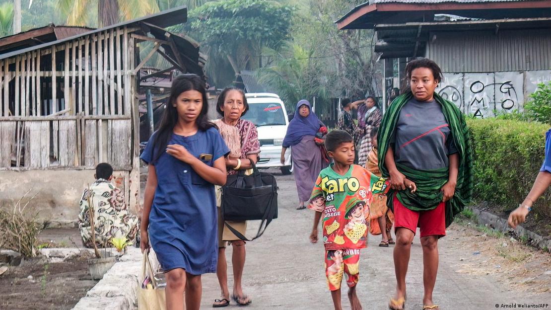 Mulheres e criança caminham com bolsas em vilarejo na Indonésia