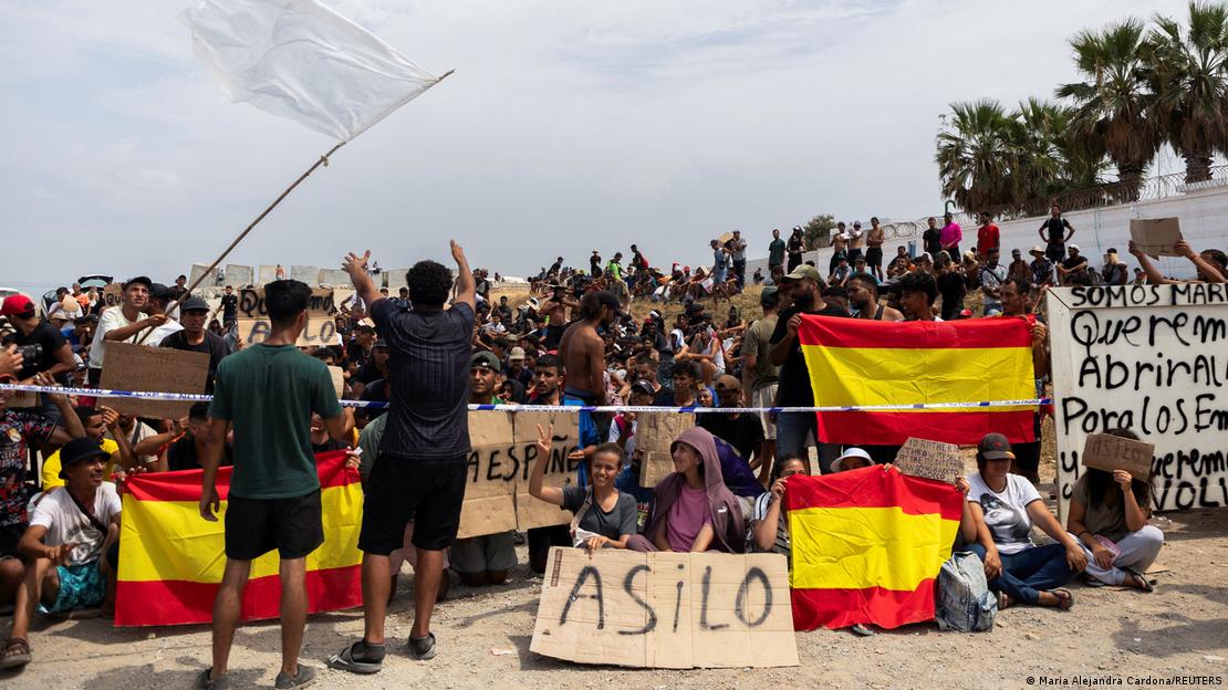 Imigrantes seguram placas com pedido de asilo em praia de Ceuta, na Espanha