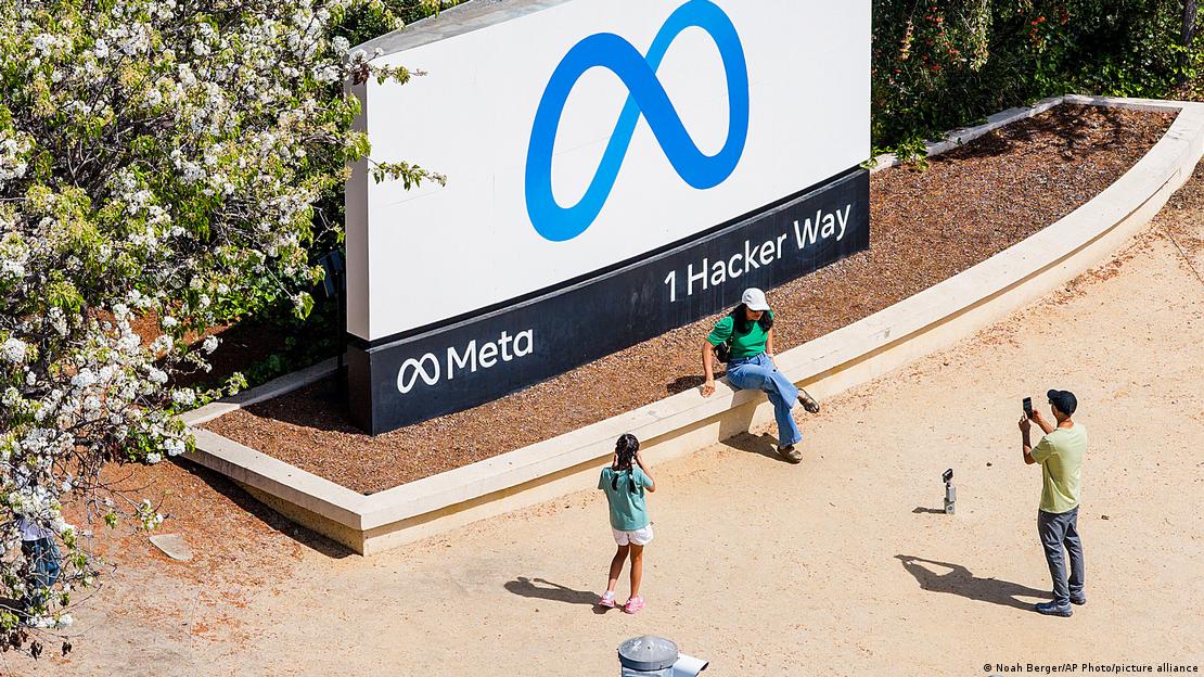 Pessoas tiram fotos em frente à placa com logo da Meta na sede da empresa