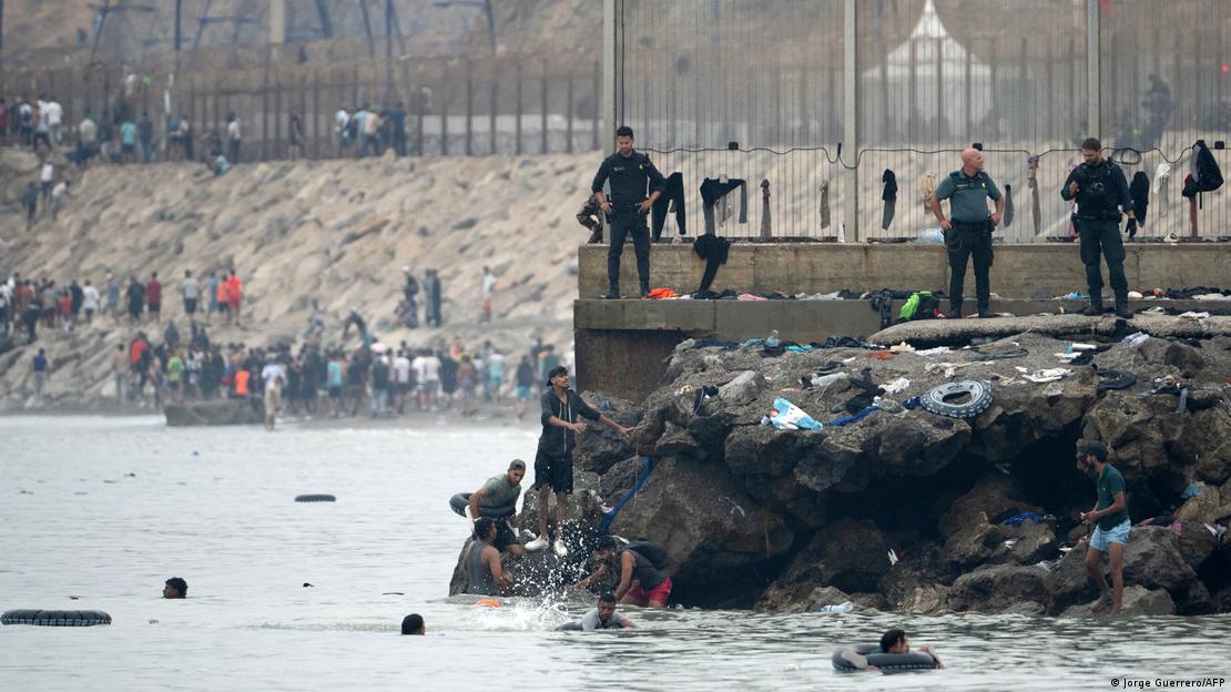 Migranten im Wasser, auf Gesteinsbrocken Sicherheitskräfte Migranten im Wasser, auf Gesteinsbrocken Sicherheitskräfte