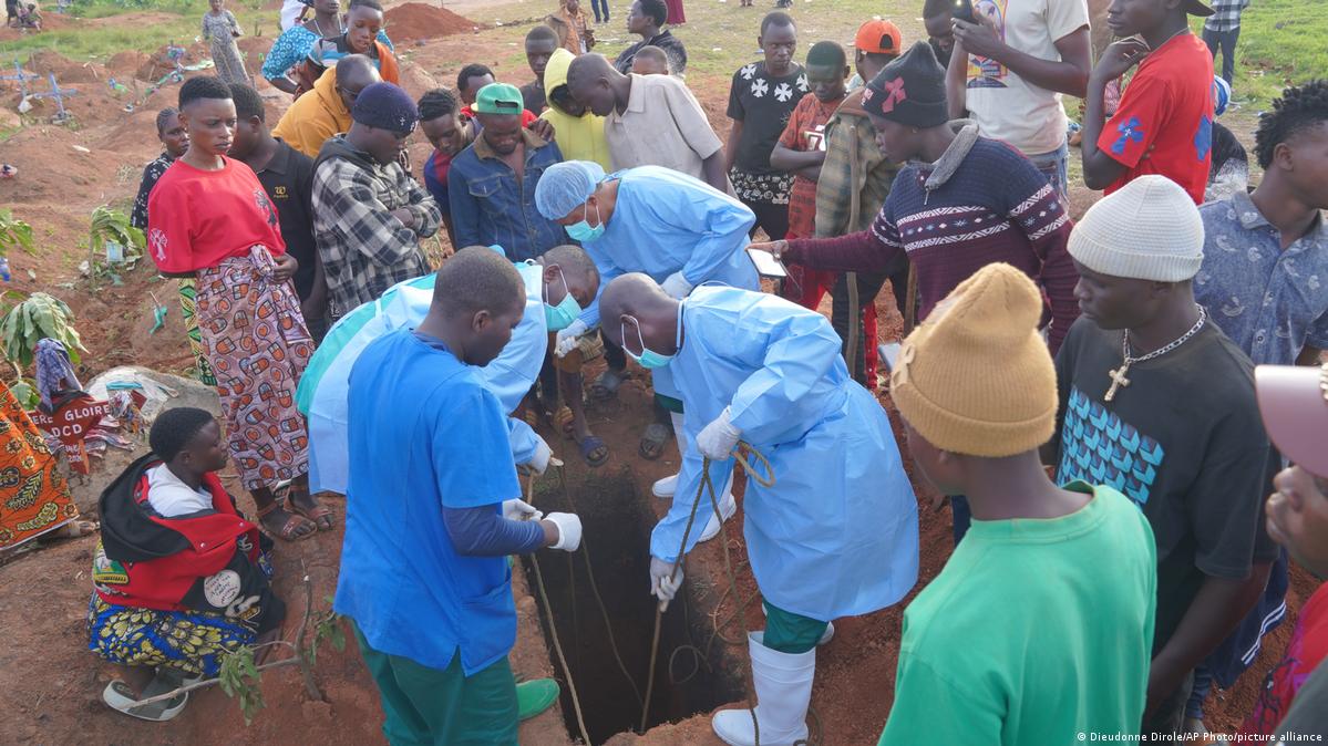 Health workers bury a deceased Ebola patient in a grave