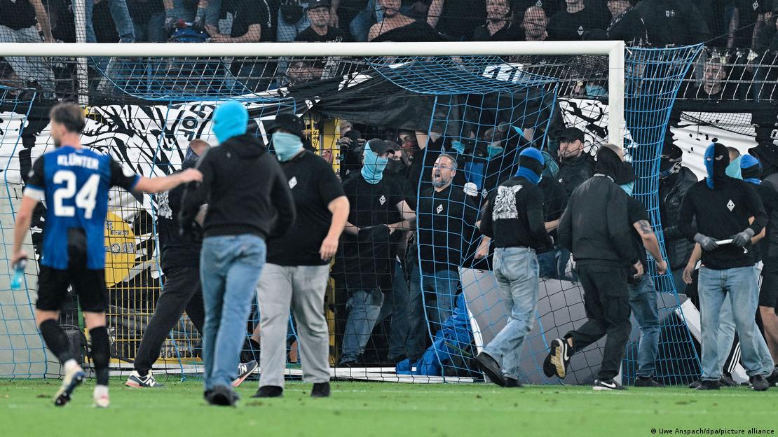 Kale arkası tribünden futbol sahasına giren, bazısı kar maskeli taraftarlar