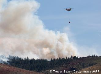Un helicóptero arroja agua sobre un incendio forestal