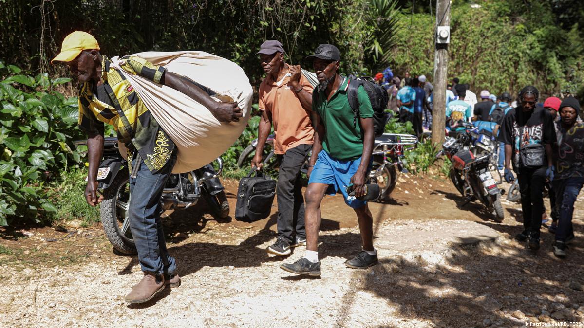 People carry their belongings as they flee their homes after a fatal overnight raid by an armed gang, on the outskirts of Port-au-Prince