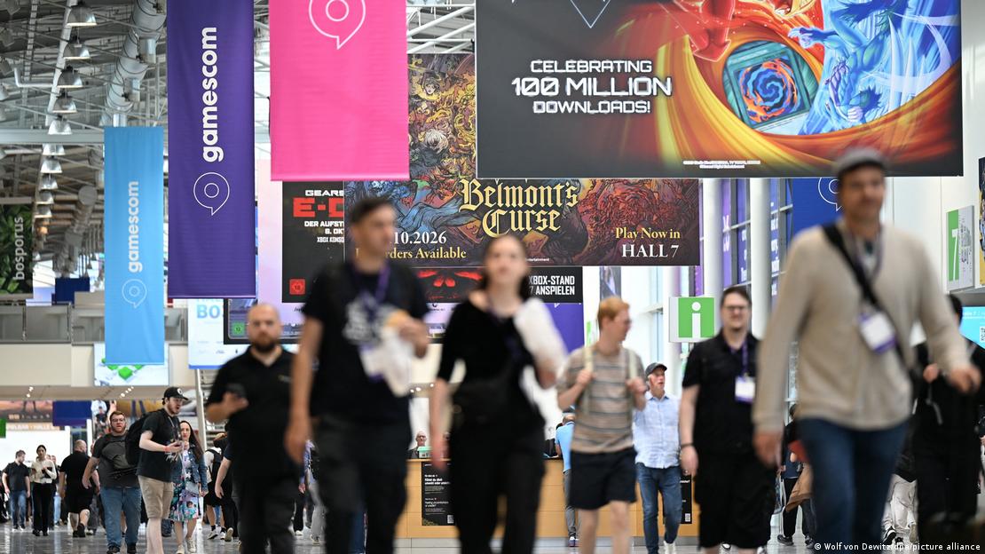 Köln'deki Gamescom fuarında ziyaretçiler, oyun şirketlerinin stantları ve büyük tanıtım ekranlarının bulunduğu fuar alanında ilerliyor.