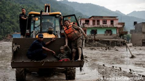 Sobreviventes são transportados em zona coberta de lama após enchentes no Nepal