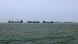 Six or seven ships lined up on the sea.