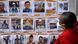 A woman stands infront of a wall full of posters of missing people A woman stands infront of a wall full of posters of missing people