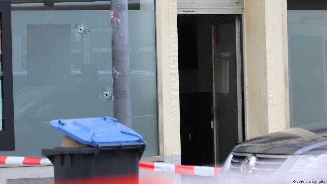 Köln'de kurşunlanan bir kıraathane polis barikatı ile çevrilmiş. Camda iki büyük kurşun deliği görünüyor 