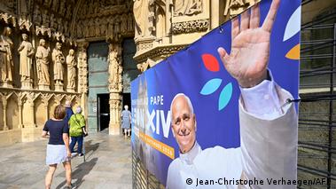 People enter the Saint-Etienne Cathedral where a banner displays a picture of Pope Leo XIV waving