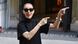 A cantura Céline Dion vestida de preto e de óculos escrutos gesticula em frente ao Hotel Royal Monceau, em Paris.