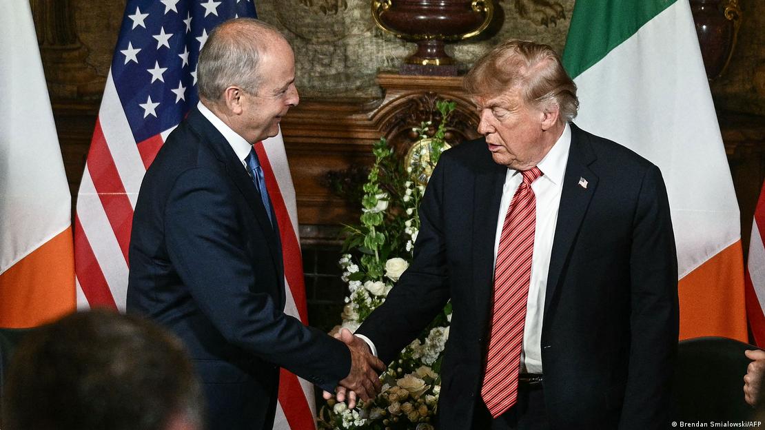 Trump estrecha la mano de Martin con las banderas de Estados Unidos e Irlanda detrás. Trump estrecha la mano de Martin con las banderas de Estados Unidos e Irlanda detrás.