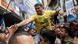 Falvio Bolsonaro, a hombros de un hombre, en una calle llena de gente, saludando con la mano a una persona que le extiende la suya. 